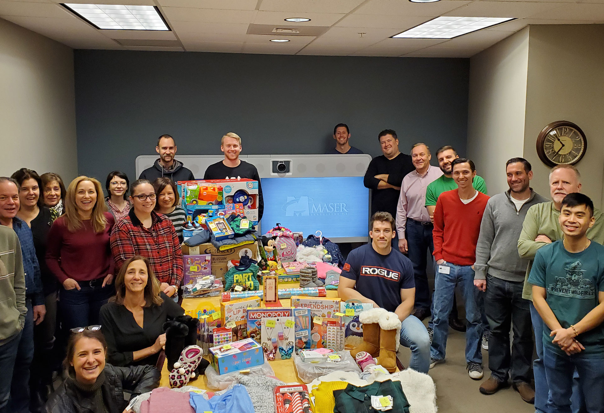 Colliers Engineering & Design Hamilton office poses for picture with presents for their Adopt-A-Family