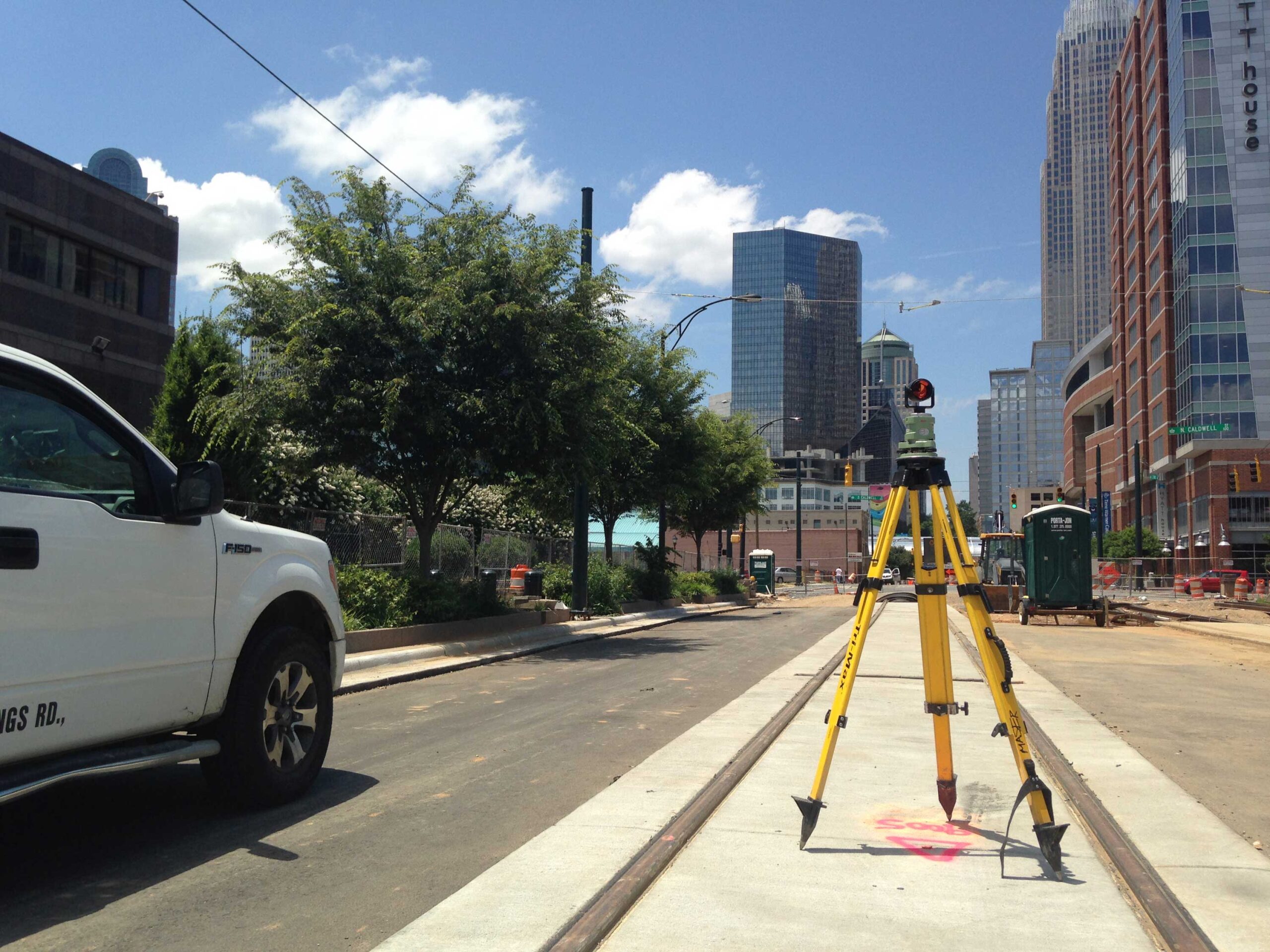 Colliers Engineering & Design truck parked next to a survey rod lined up along a railroad track.