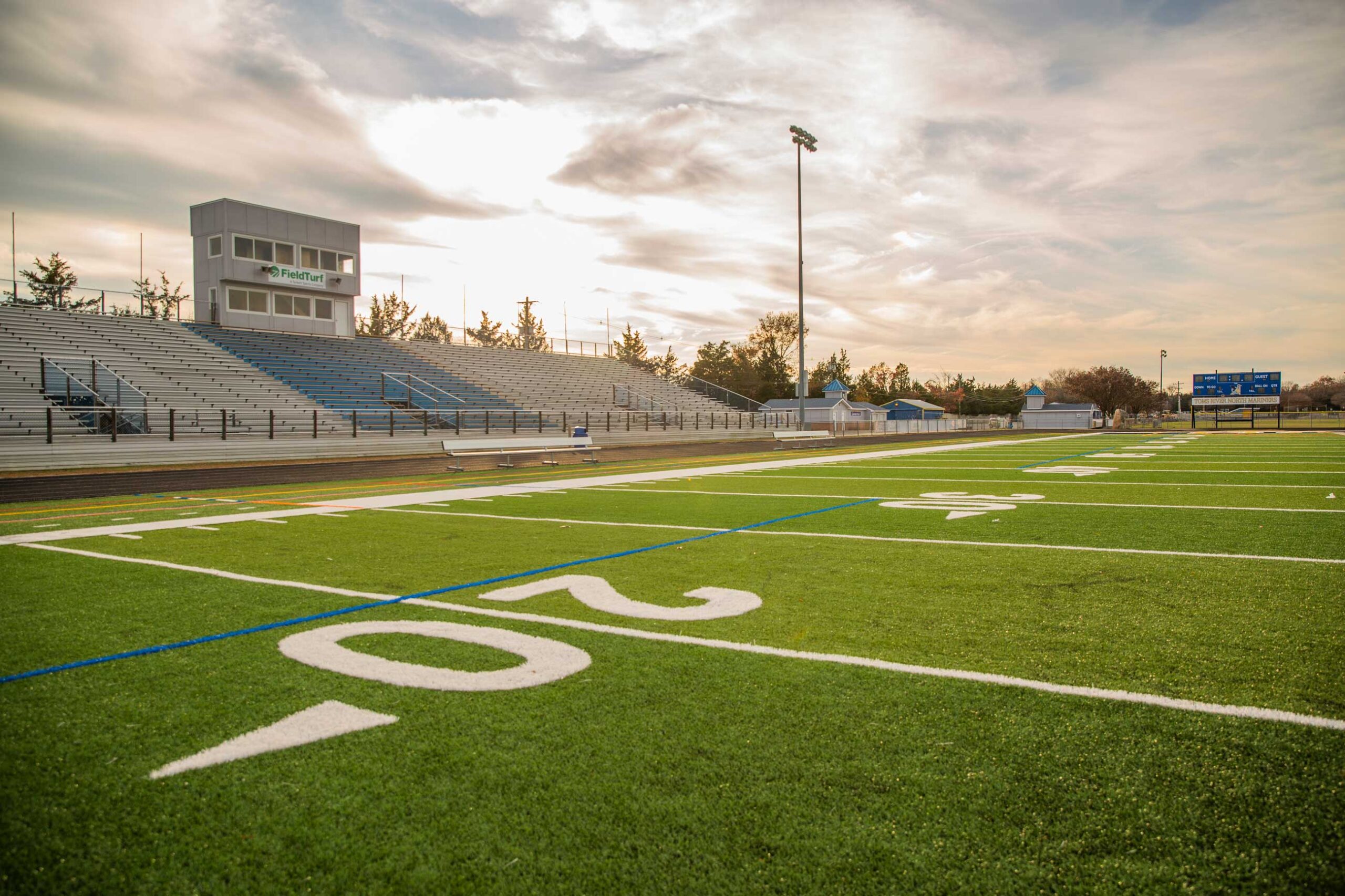 Closeup of synthetic turf athletic field with bleachers in the background.