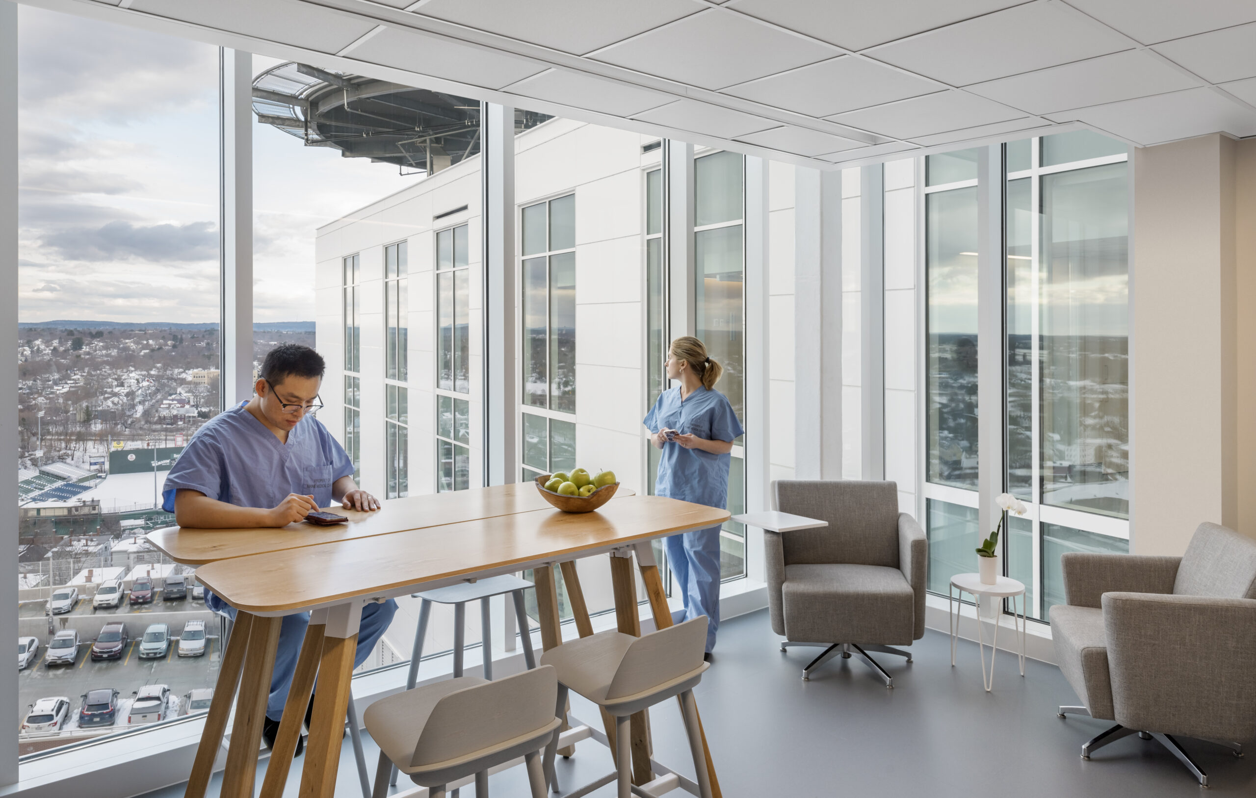 Male and female nurse taking a break in a well lit respite room overlooking the town.