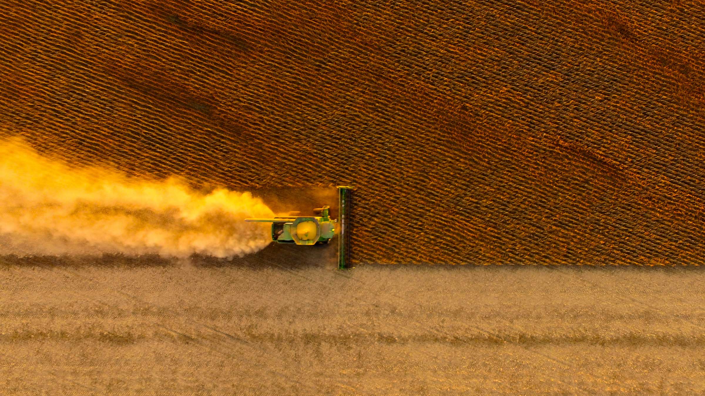 Aerial view of crop field with machinery fertilizing the land.