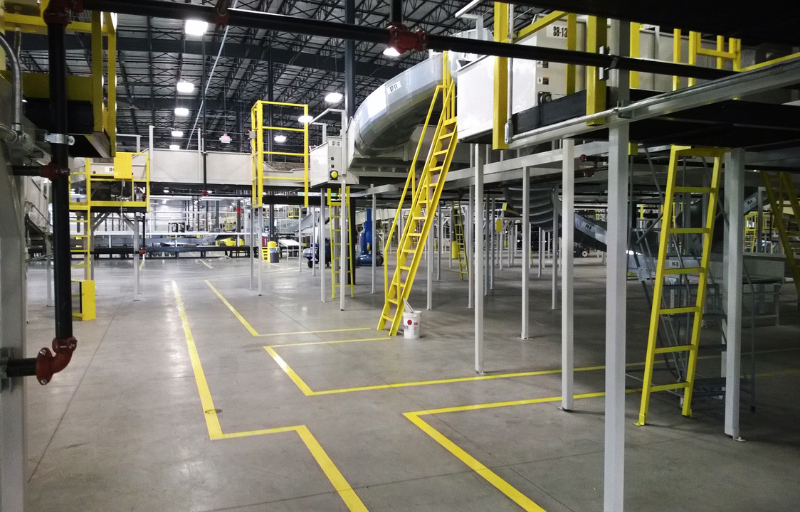 Distribution center with conveyor belts and yellow ladders.