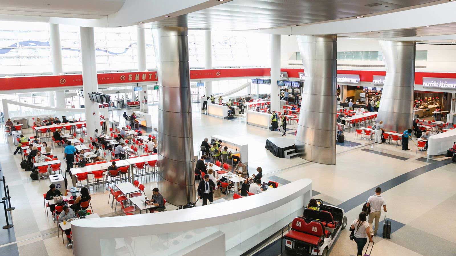 Travelers mingling around the airport terminal food court.