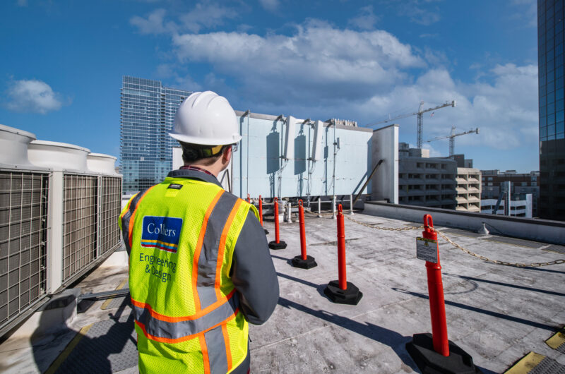 Telecommunications engineer wearing a bright yellow Colliers Engineering & Design safety vest standing on top of the Hilton Hotel in Nashville, Tennessee.
