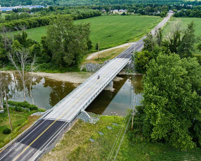 Motorcycle riding across local bridge over river