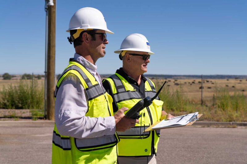 Two professionals in the field equipped with safety gear