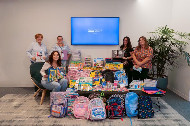 Organizers stand in front of items collected for a school drive