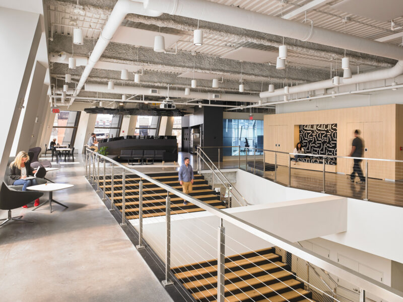 Interior of the Partners + Napier corporate headquarters. Individuals descend the stairs and utilize the public seating, making the most of the available space.