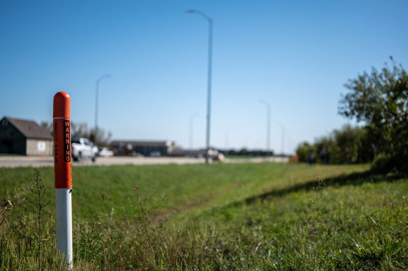 Marker post for underground internet optics line along a road ditch. 