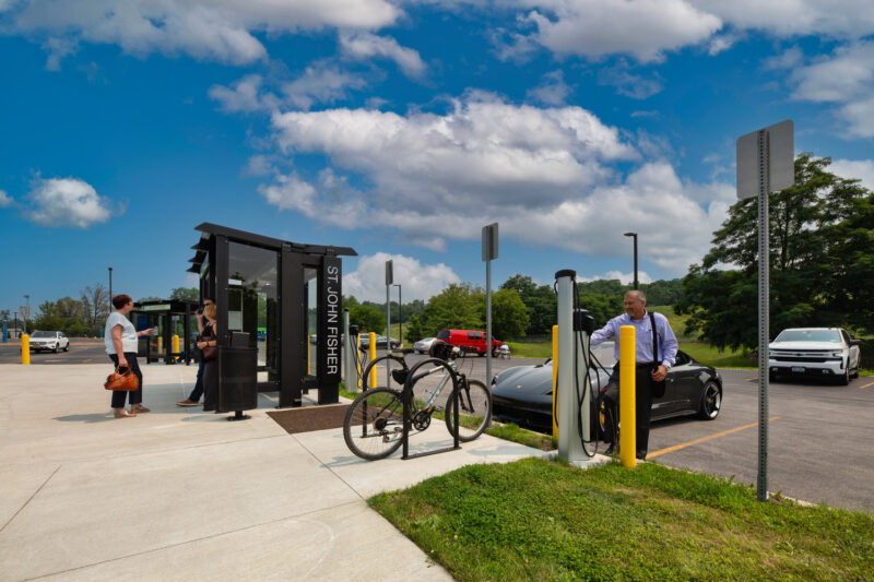 Transit hub encompasses a shaded bus stop, bike racks, and EV chargers.