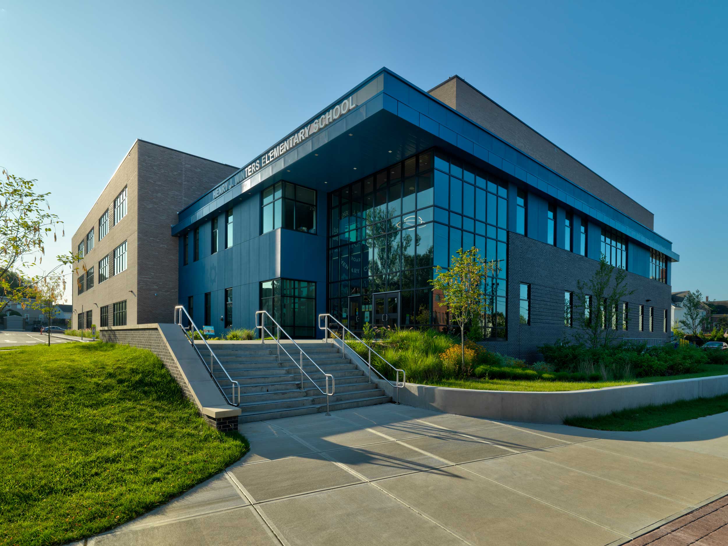 A sunny day with a clear blue sky featuring a staircase leading to the Henry J. Winters Elementary school.